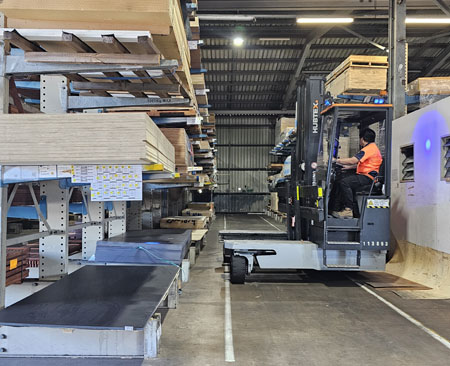 A man driving a forklift to select a piece of structural ply for the 'Force of Nature' artwork by Maria.