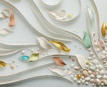 Detail from a three-panel ceramic-on-glass artwork by Maria called 'Beneath your Feet'. Many ceramic ribbons, leaves, and pebbles evoke the flow of water rising from beneath the earth.
