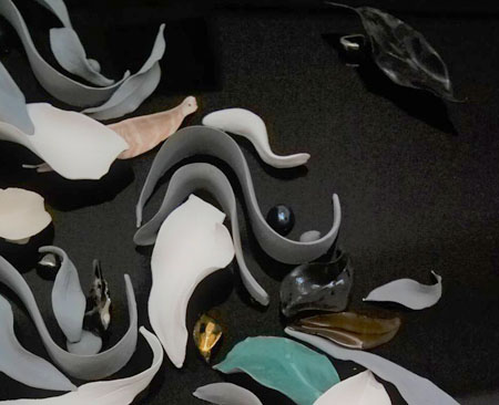 Lustrous and glazed ceramic leaves and ribbons attached to black glass. A detailed view of an artwork called 'Eternity'.