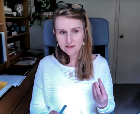 A person gesturing while looking towards the screen in a video meeting.