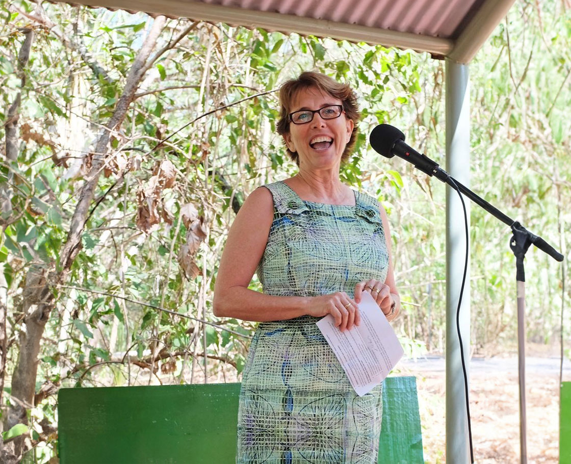 Artist Maria Kraatz speaks into a microphone in a bushland setting at the opening of the Artist-in-the-Park program at the Territory Wildlife Park.