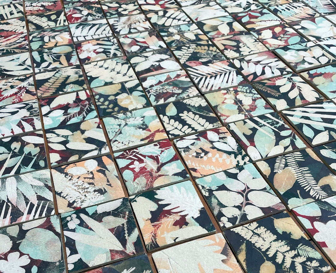 An array of hand-made custom ceramic tiles featuring silohuettes of leaves and flowers.